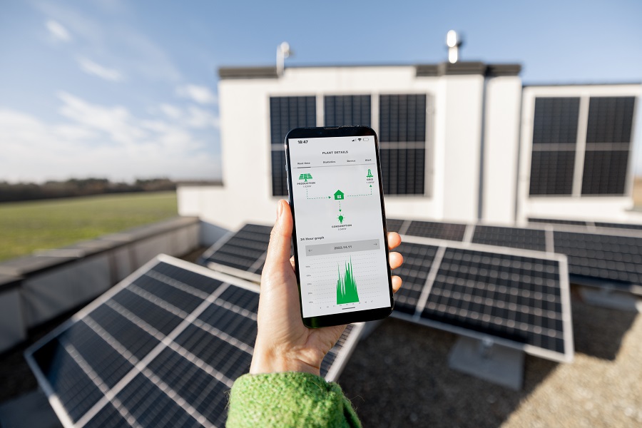 Woman monitors energy production from the solar power plant with mobile phone. Close-up view on phone screen with running program. Concept of remote control of solar energy production